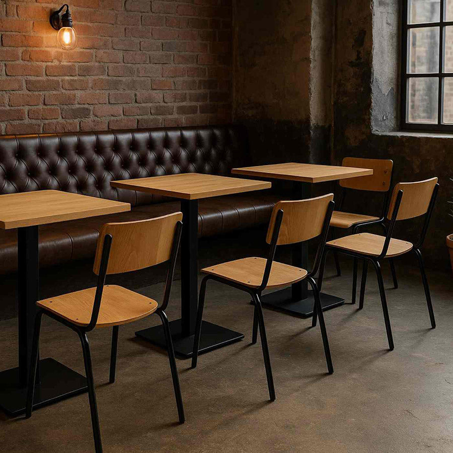 Restaurant interior with wooden tables and chairs against a brick wall.