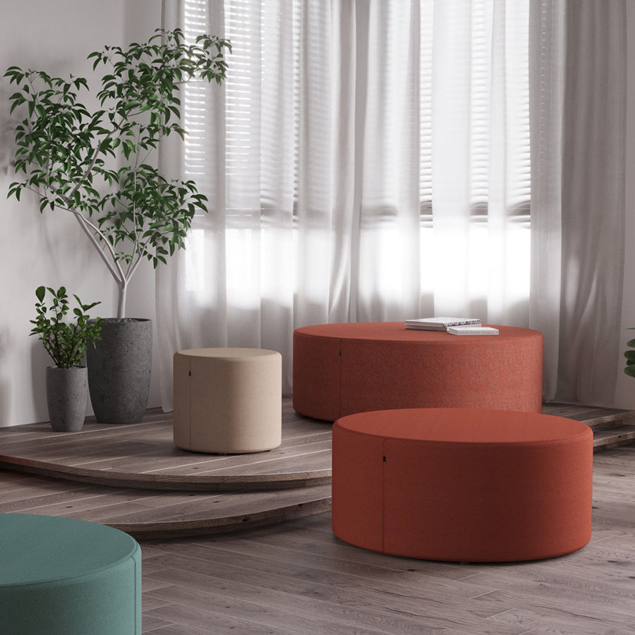 Modern living room with round orange Point ottomans, a beige Point ottoman, and potted plants.