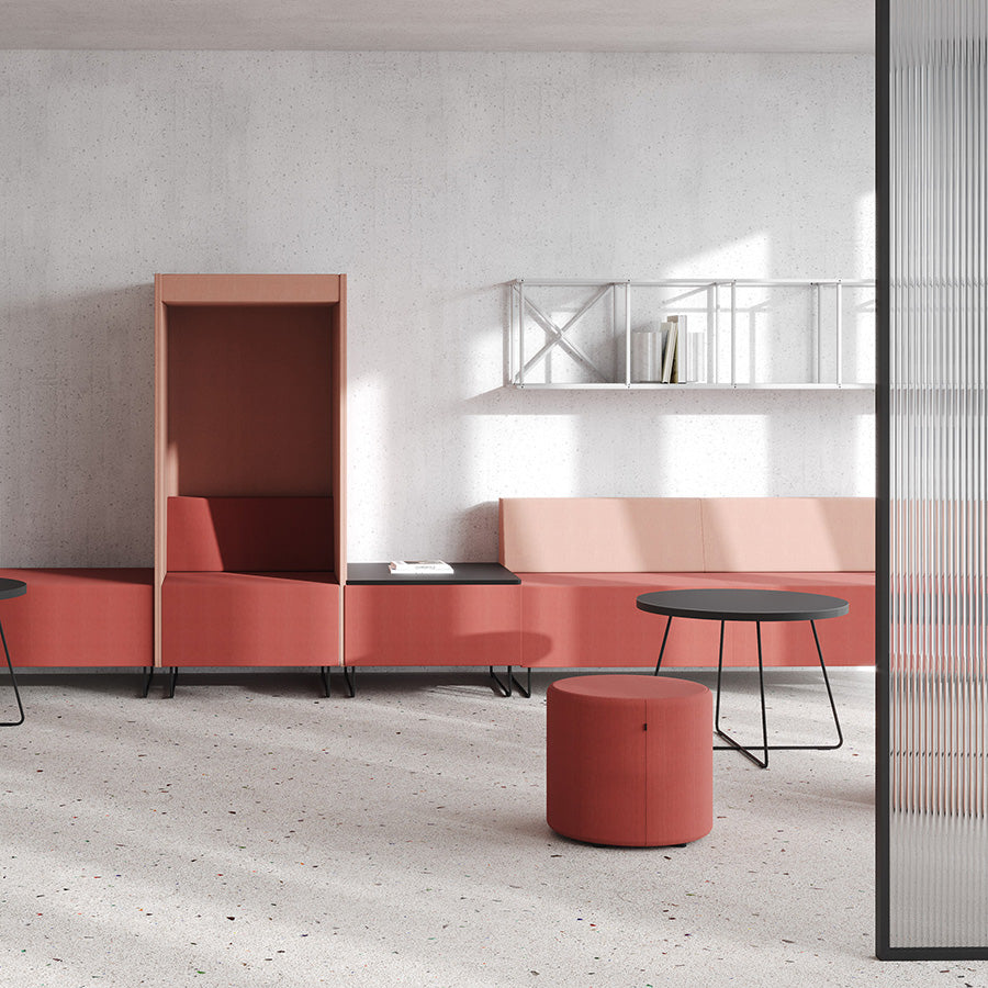 Modern office space with pink modular furniture, pink Point ottoman and a black table.