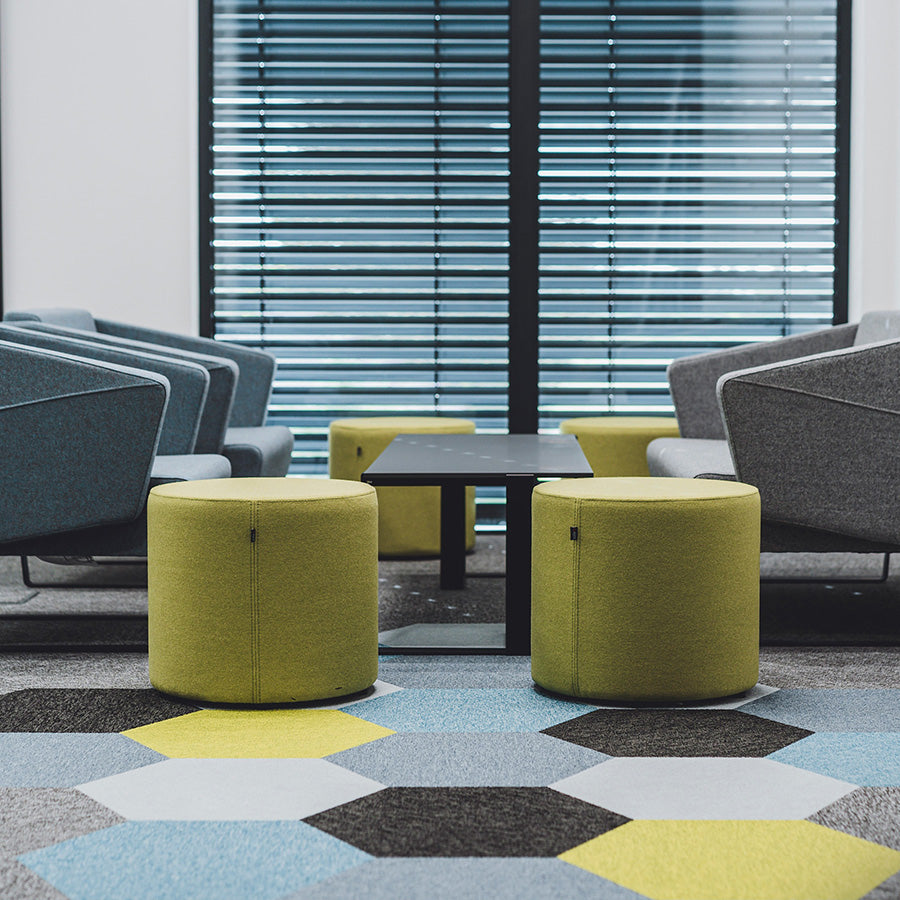 Modern office space with gray chairs, green Point ottomans, and a hexagonal patterned floor.