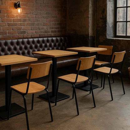 Restaurant interior with wooden tables and chairs against a brick wall.
