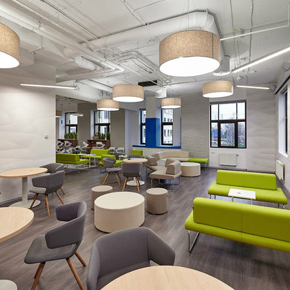 Modern office space with green sofas, gray chairs, round tables and Point Ottomans.